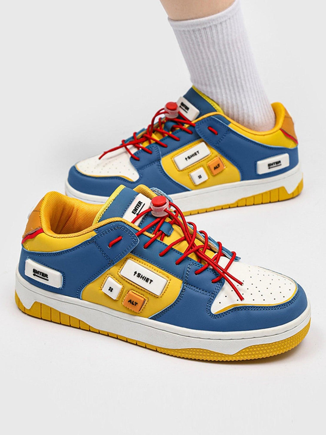 TALISHKO skate shoes in bold blue and yellow, featuring red laces and unique button details.