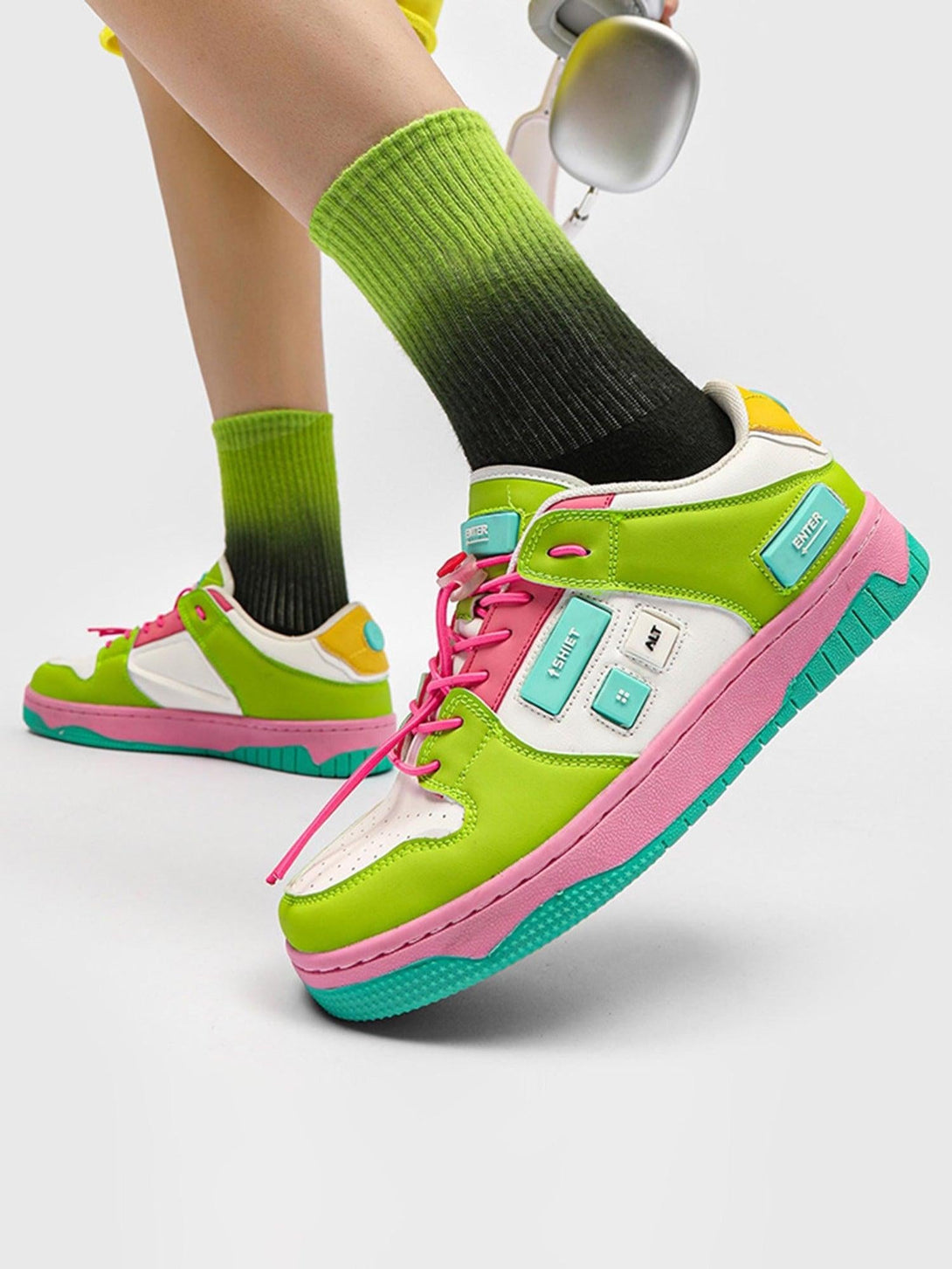 TALISHKO skate shoes in vibrant green and pink, paired with ombre socks and sleek headphones.