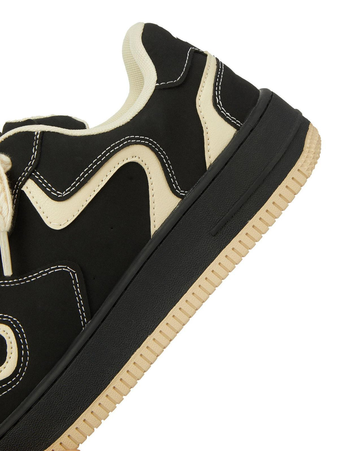 Intricate look at TALISHKO skateboard shoes in black with cream detailing and textured sole.