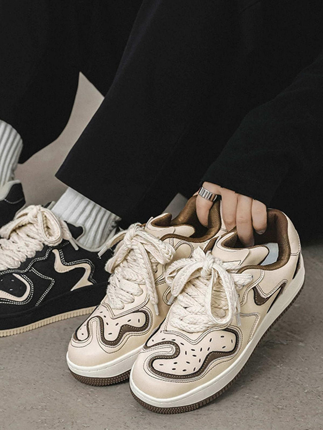 Model showcasing TALISHKO skateboard shoes in beige with brown accents and unique lace design.