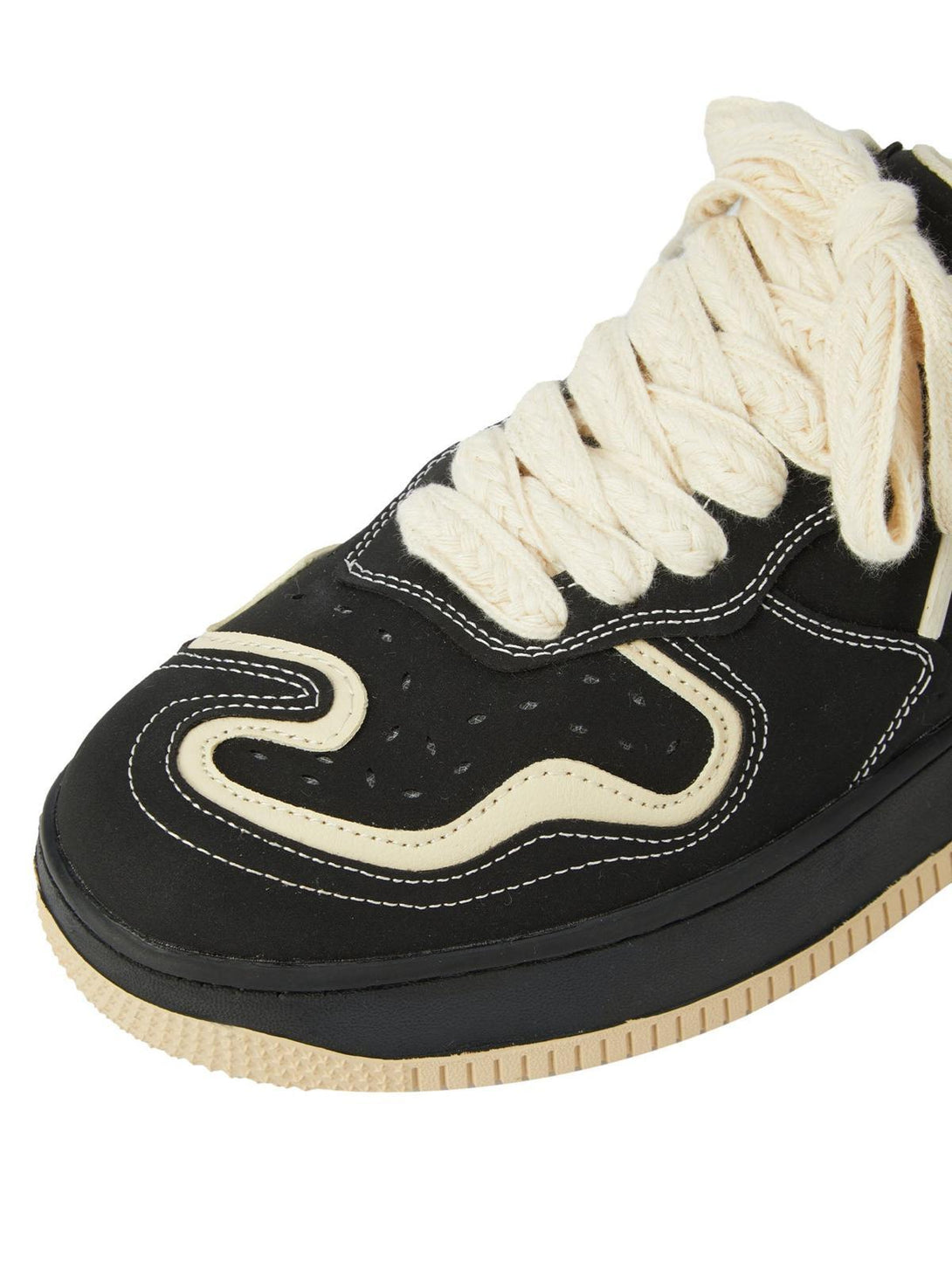 A close-up of TALISHKO skateboard shoes highlighting cream laces and bold black detailing.