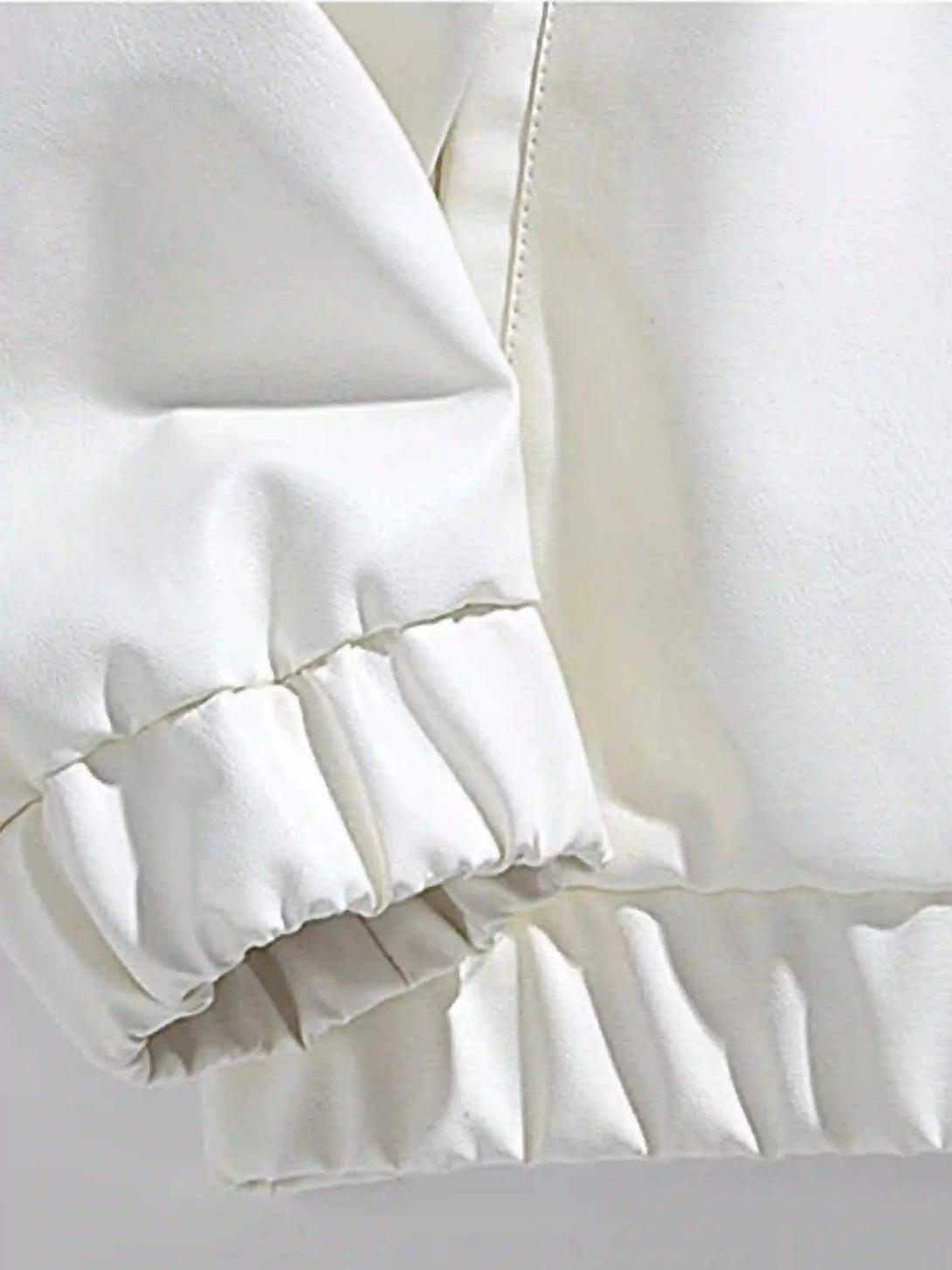 Focusing on the elastic cuff detail of a white racing baseball jacket by TALISHKO.