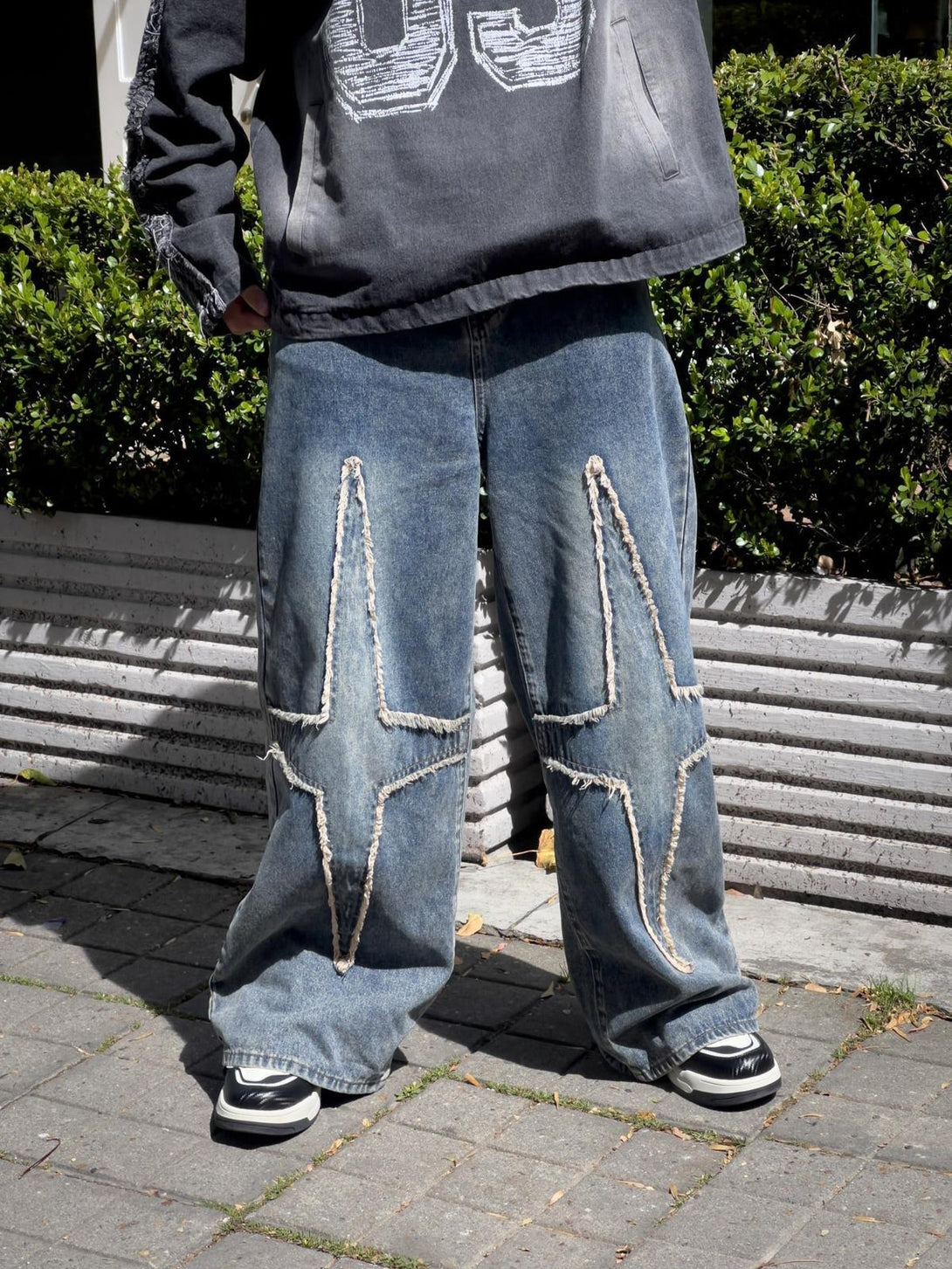 Model in TALISHKO star-patterned jeans with distressed details and wide-leg fit.