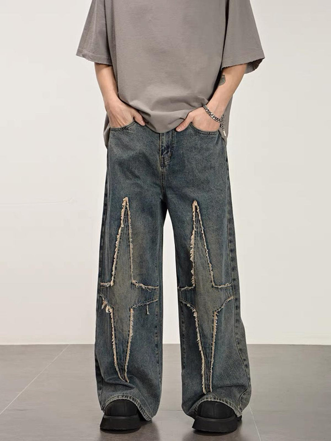 Model wearing TALISHKO star-patterned washed jeans with distressed details and wide-leg fit.