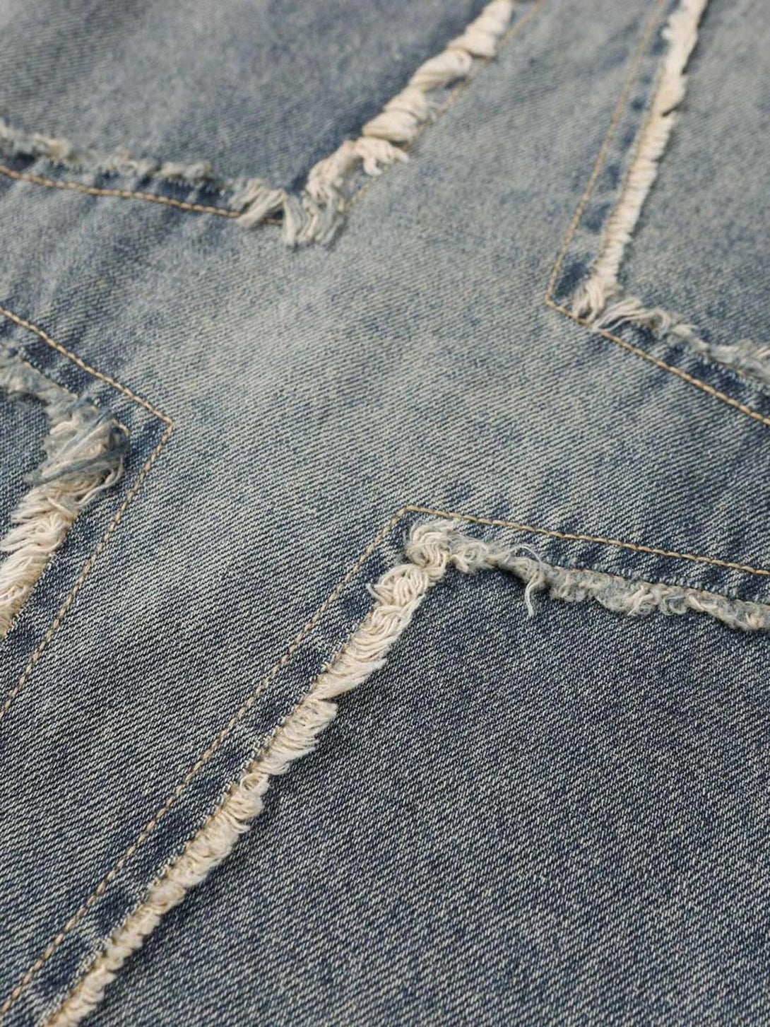 Intricate look at TALISHKO star-patterned jeans, highlighting distressed texture and stitching.