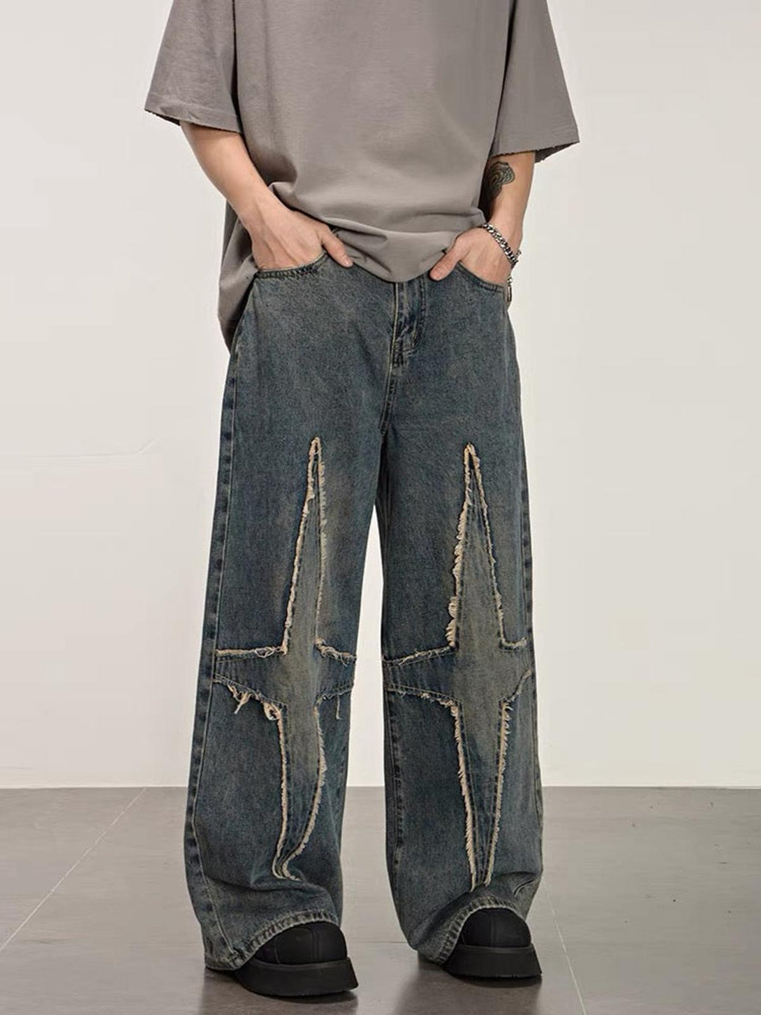 Model wearing TALISHKO washed jeans with star pattern and distressed wide-leg design.