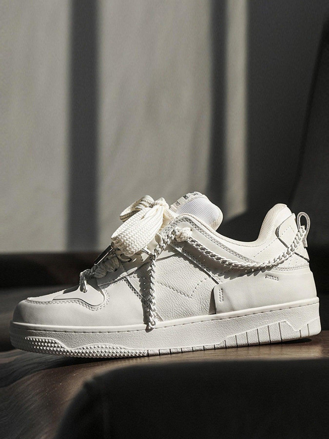 TALISHKO board shoes in white with chain details, captured in a soft-lit side view.