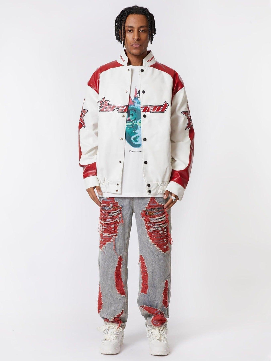 Model wearing TALISHKO varsity jacket with distressed denim jeans featuring bold red patches.