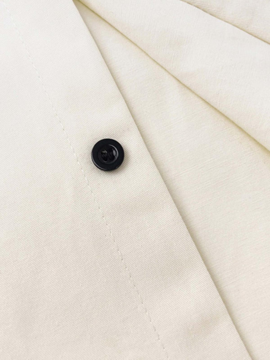 Detailed fabric and stitching on a TALISHKO short-sleeved shirt, featuring a black button.