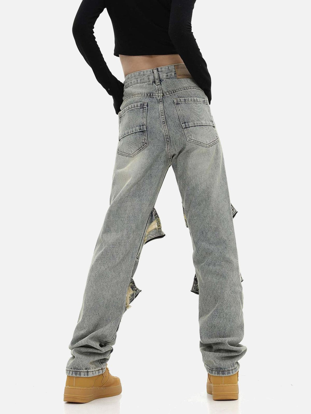 Model in TALISHKO washed denim pants, highlighting back view with torn accents and relaxed fit.