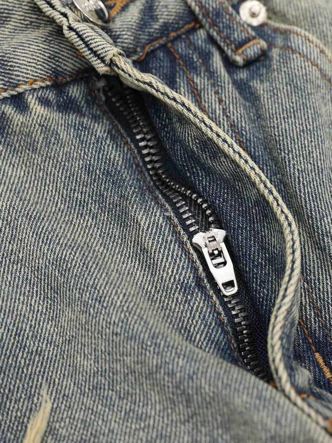 A detailed view of TALISHKO's washed denim pants, highlighting the zipper and textured fabric.