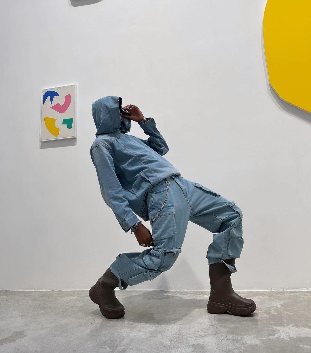 Model wearing a TALISHKO washed denim hoodie, styled with cargo pants and brown boots.