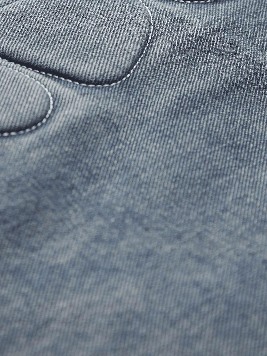 Zoomed-in texture of TALISHKO jeans, highlighting patchwork and washed denim details.