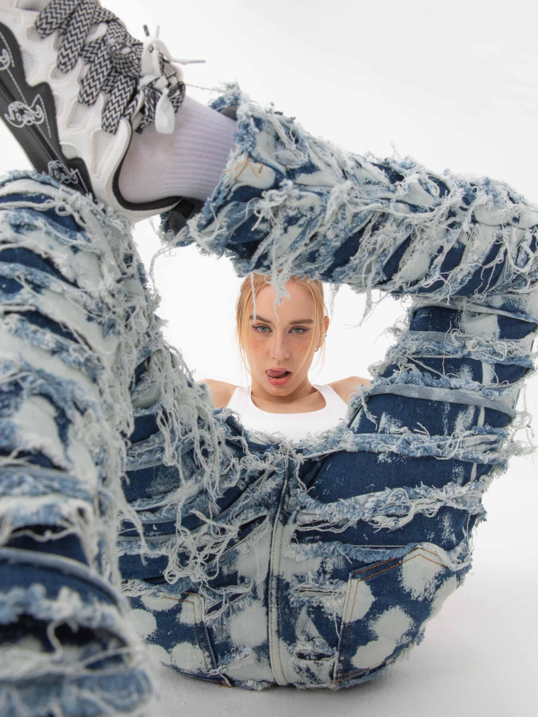 Model in TALISHKO distressed jeans, highlighting a bold streetwear look with sneakers.