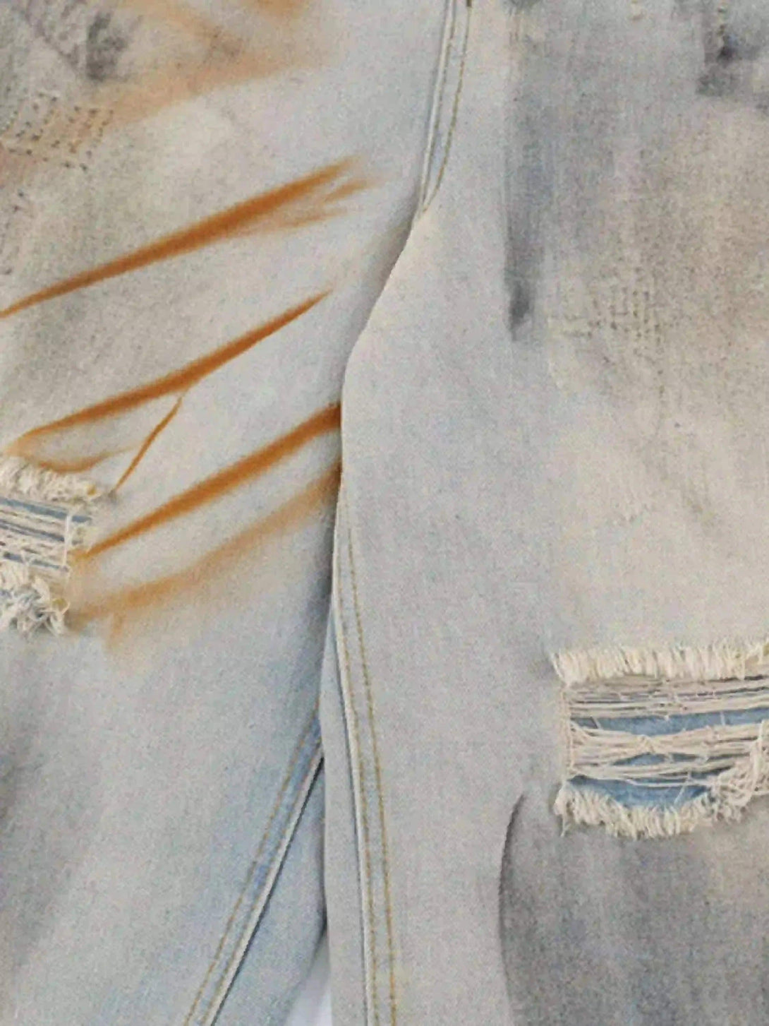 Focusing on the distressed texture and mud-dyed detail of TALISHKO denim shorts.