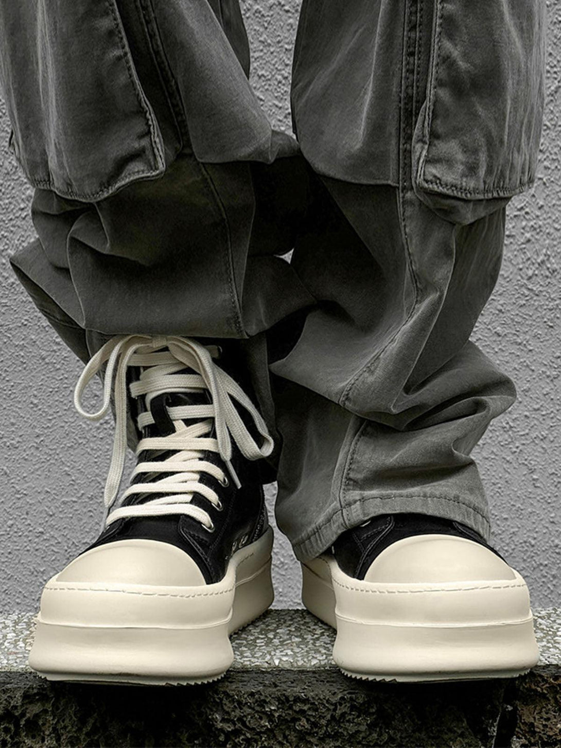 High-top platform sneakers by TALISHKO, paired with loose gray pants for a casual vibe.