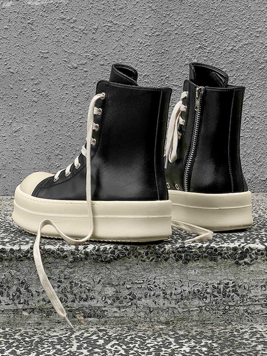 High-top platform sneakers by TALISHKO, featuring white soles and laces on a textured step.