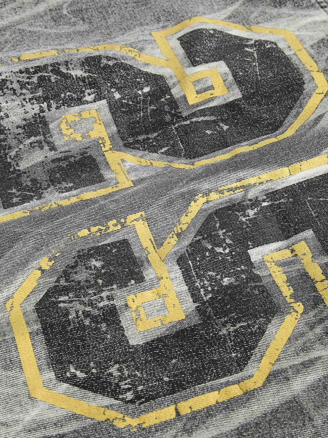 Zoomed-in texture of the distressed fabric with bold graphics on TALISHKO's denim jacket.