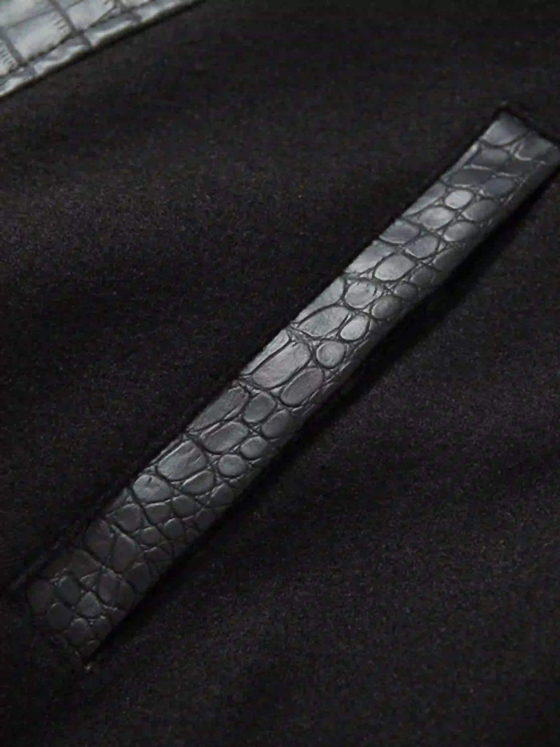 A tight crop highlighting TALISHKO jacket's crocodile-embossed leather texture detail.