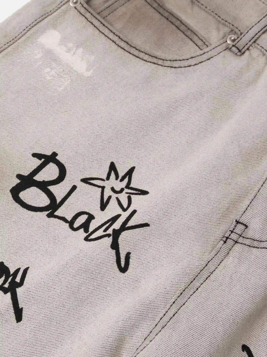 A close-up of TALISHKO graffiti distressed jeans, showcasing unique black text and designs.