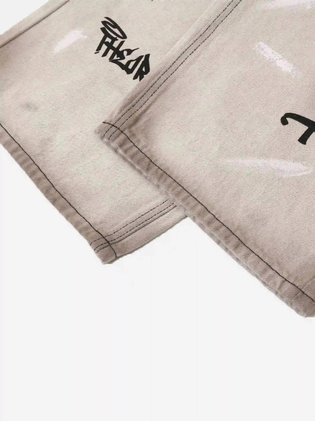 A tight crop highlighting the artistic black text on TALISHKO graffiti distressed jeans.