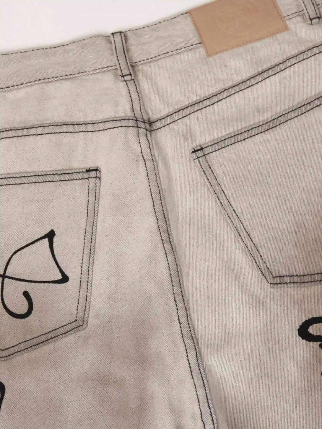 Back view of TALISHKO graffiti distressed jeans, highlighting unique black designs and stitching.