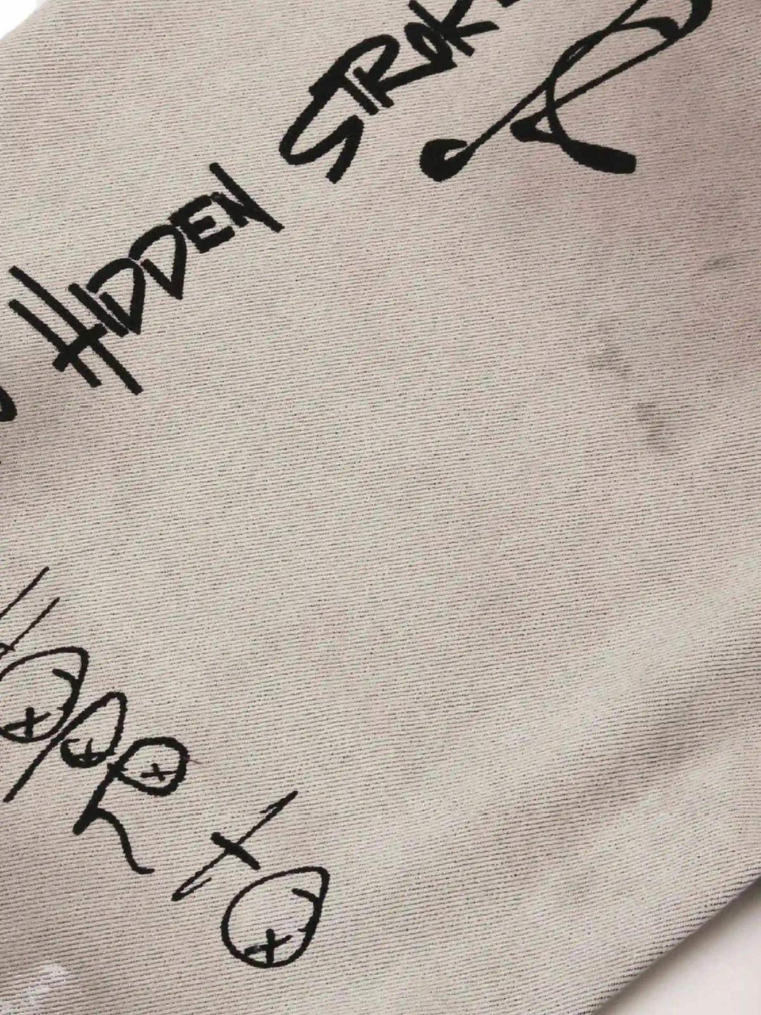 Unique black graffiti text design on TALISHKO jeans, showcasing artistic detail.