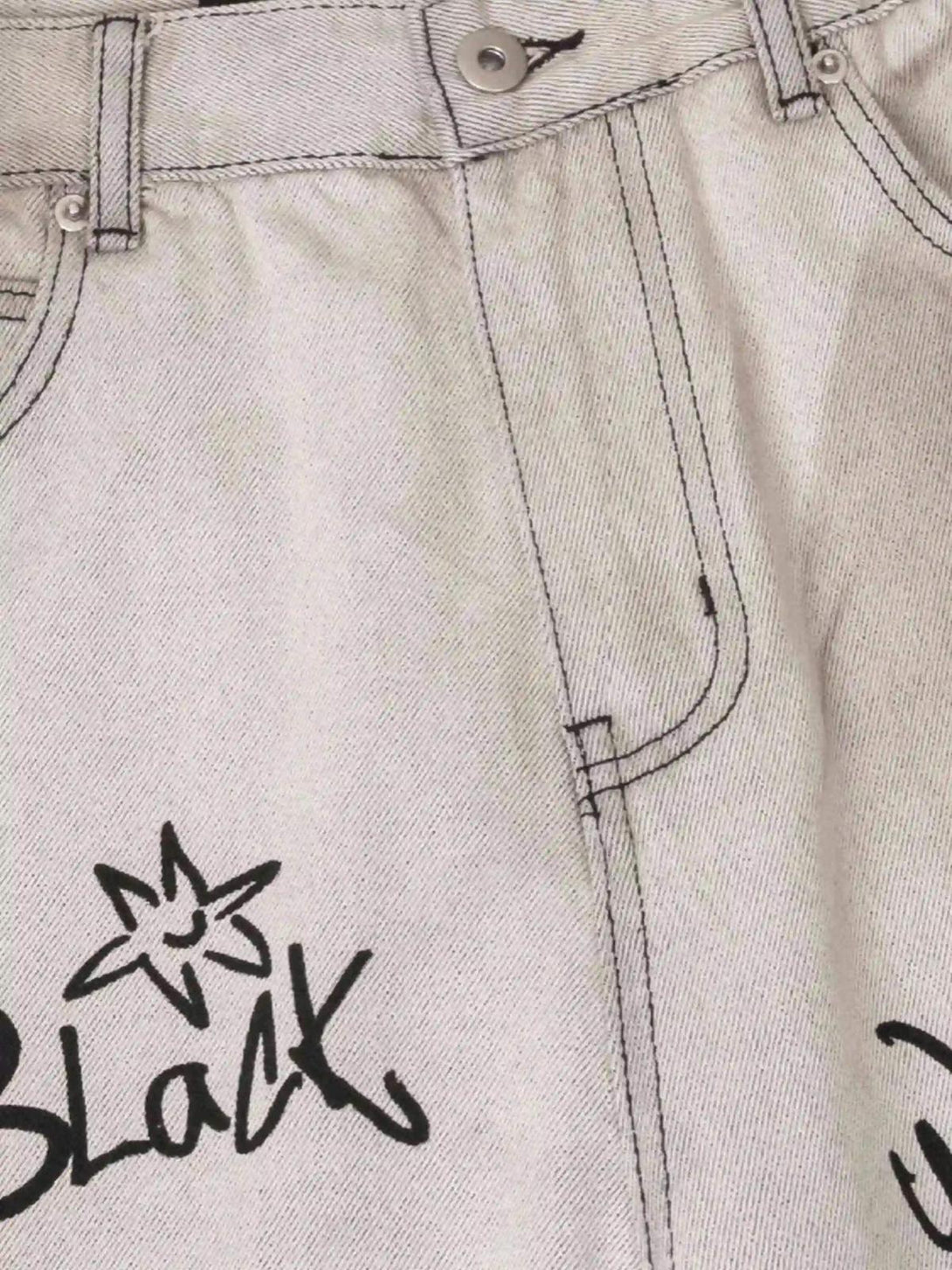 Detailed fabric and stitching on TALISHKO graffiti distressed jeans, featuring artistic black text.