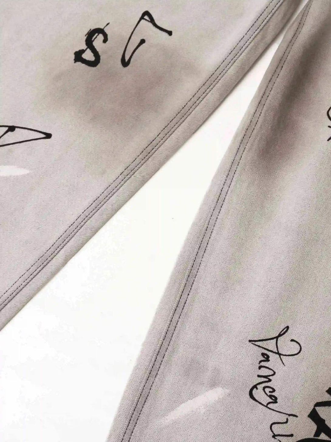 Detailed fabric and stitching on TALISHKO jeans, showcasing artistic black graffiti designs.