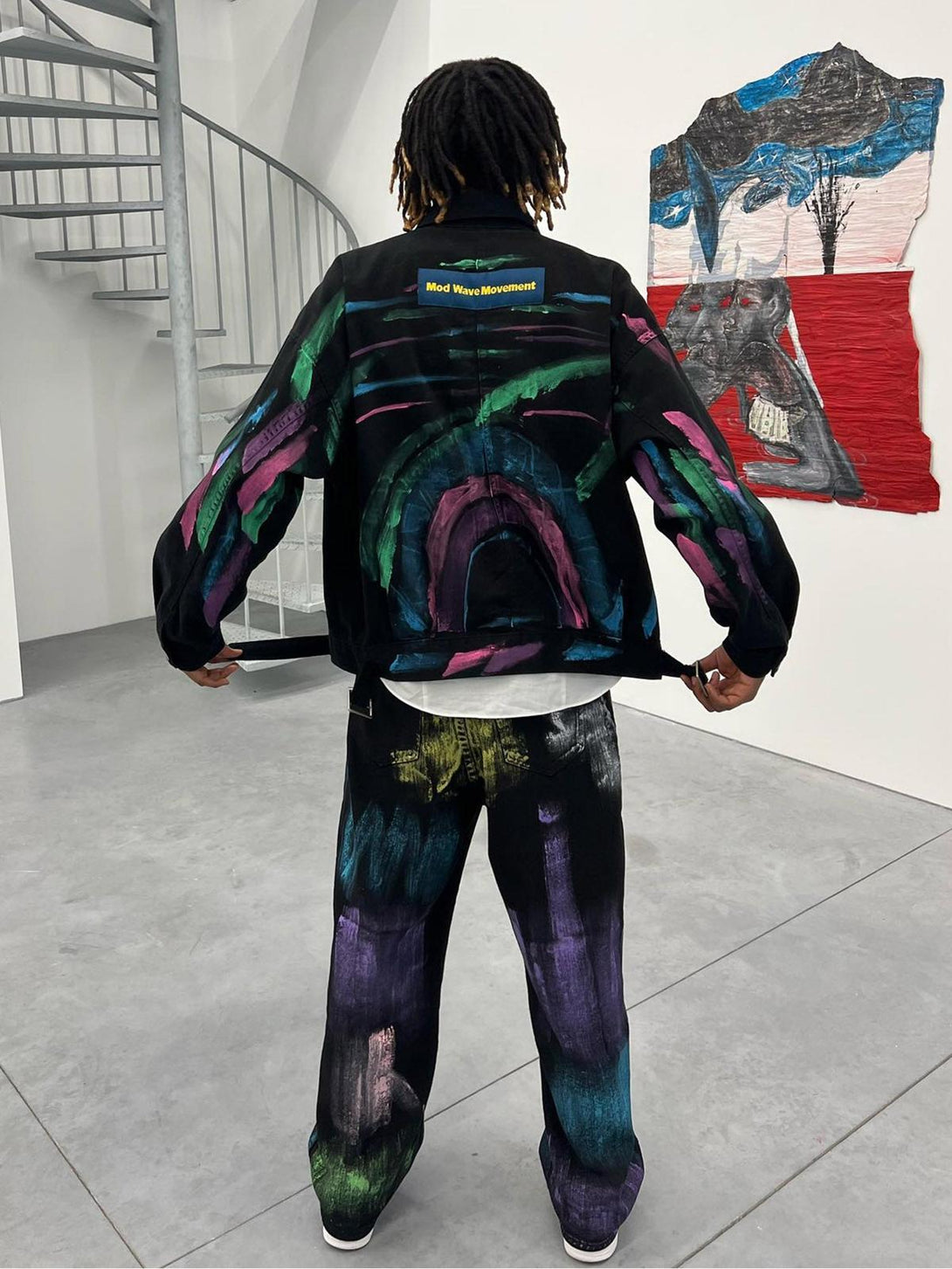 A model displays the back of TALISHKO's hand-painted graffiti denim jacket with colorful designs.