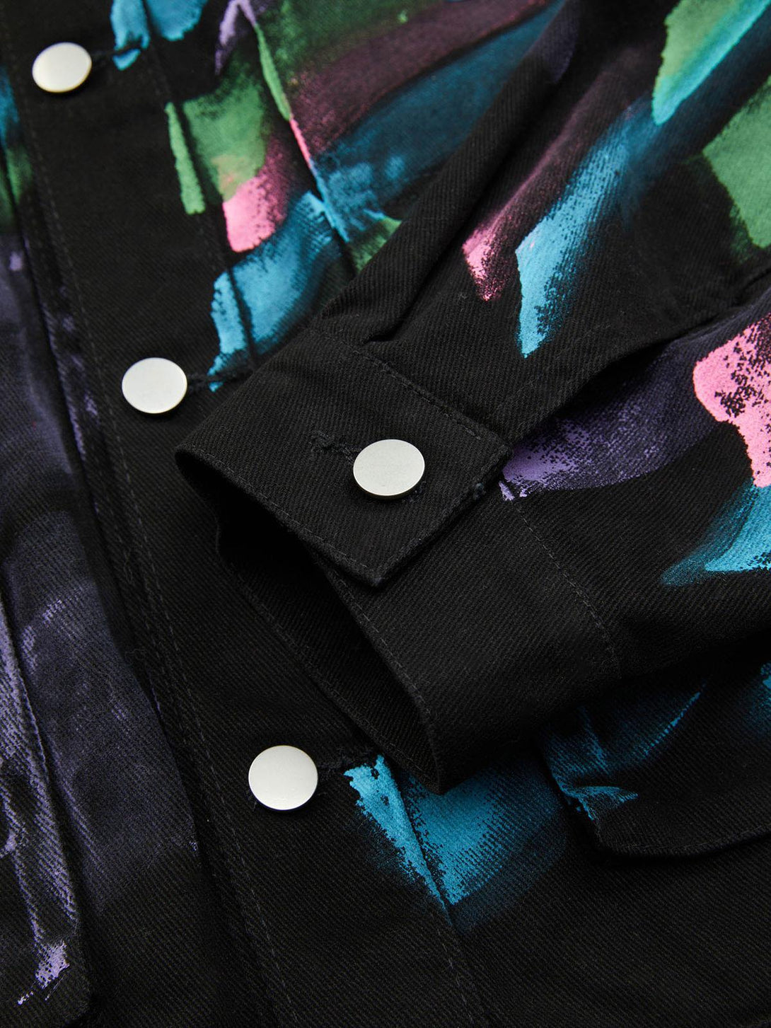 Intricate look at TALISHKO's graffiti denim jacket, featuring bold hand-painted colors and silver buttons.