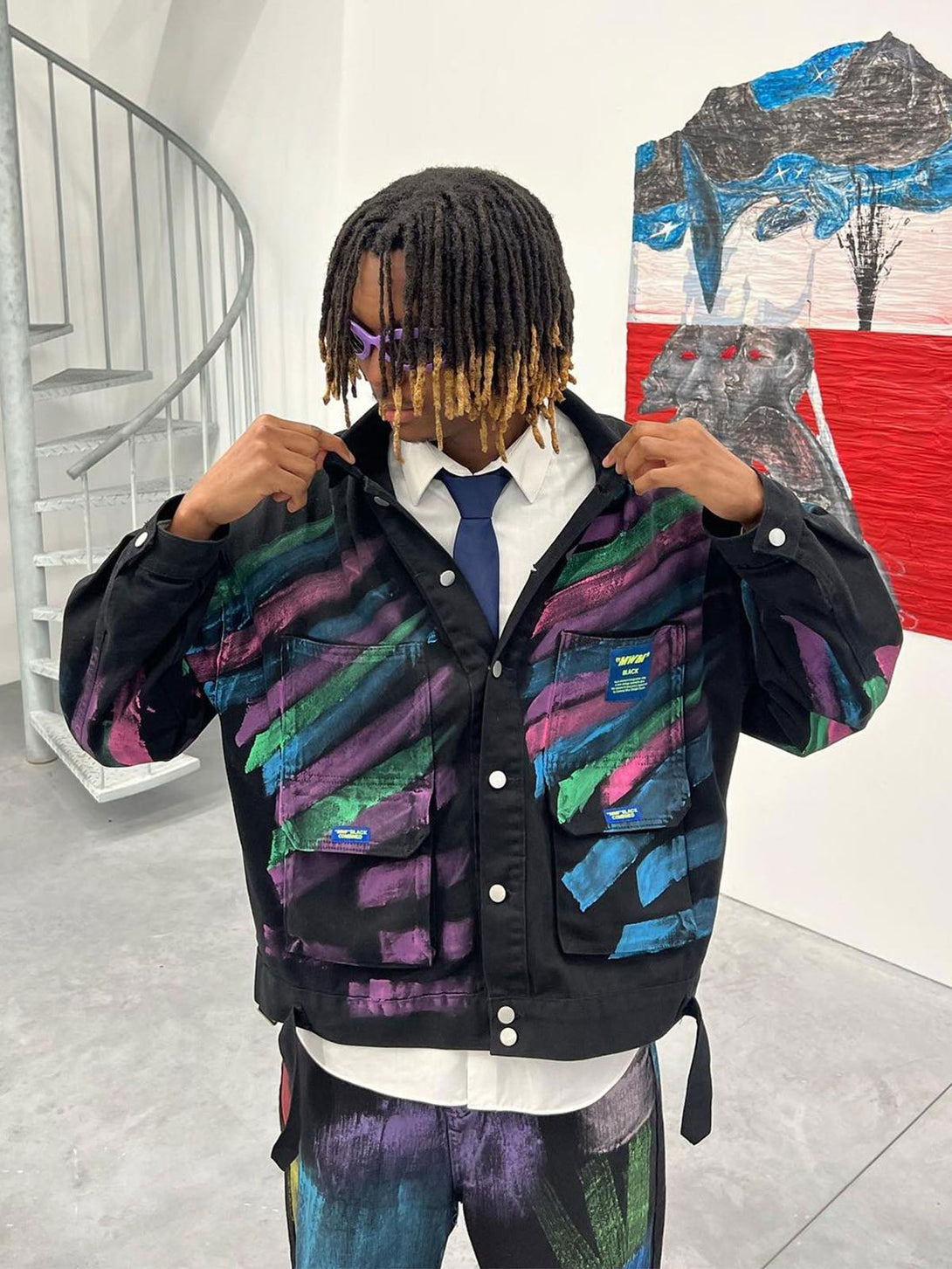 A model wearing a TALISHKO hand-painted graffiti denim jacket with vibrant, artistic patterns.