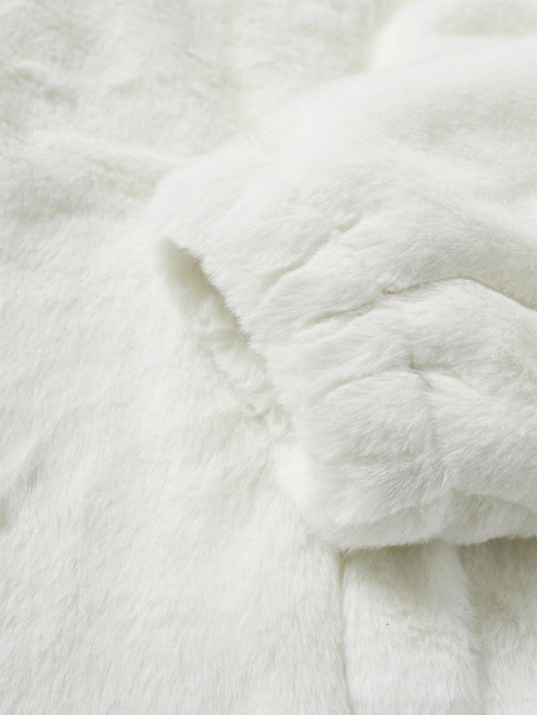 Zoomed-in texture of a white fur jacket by TALISHKO, highlighting its soft and plush fabric.