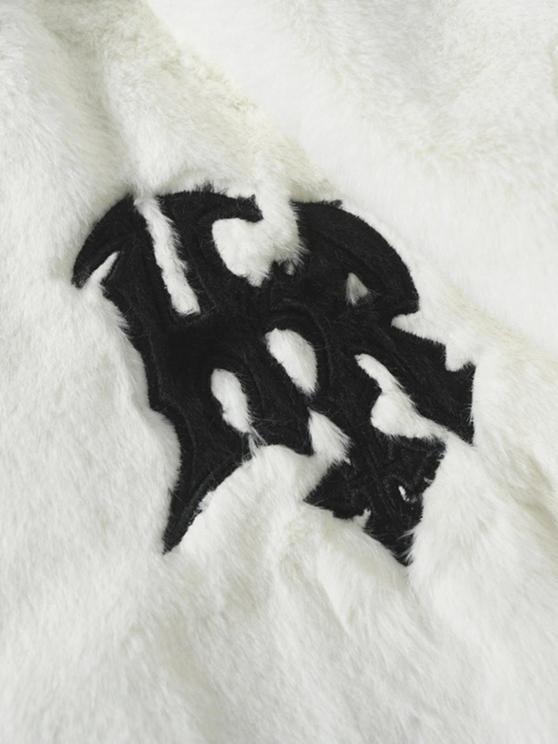 Intricate look at the black letter design on a white fur jacket by TALISHKO.