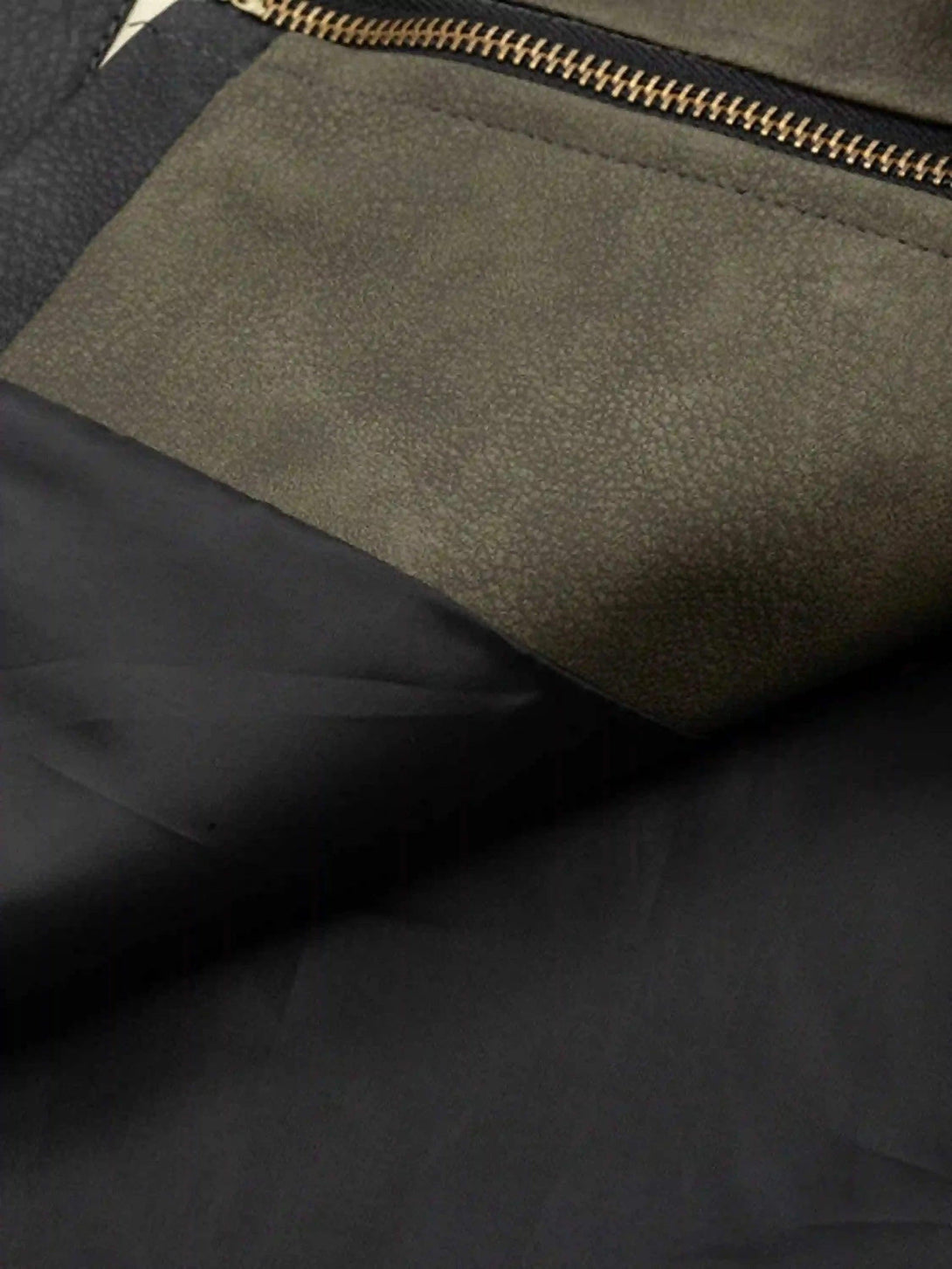 A tight crop highlighting the textured fabric and zipper detail of TALISHKO's motorcycle jacket.