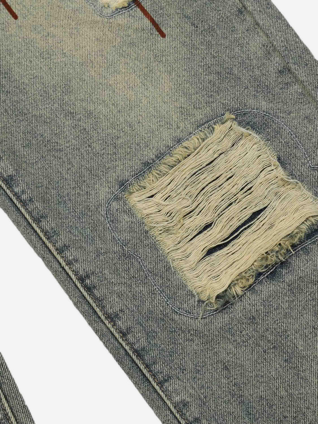 Focusing on the distressed patch detail of TALISHKO's retro denim jeans, showcasing texture.