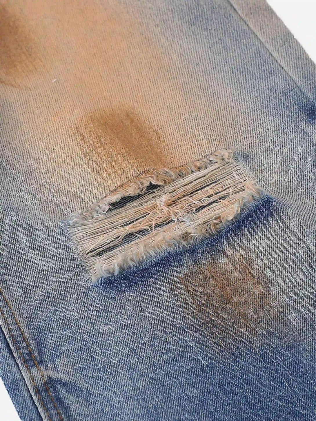 Detailed fabric and stitching of TALISHKO hip-hop ripped jeans, showcasing distressed design.