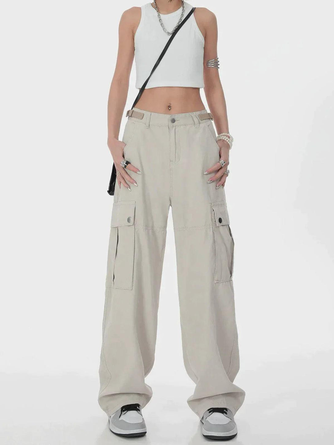 Model in TALISHKO hip hop cargo pants and white crop top, accessorized for a trendy street look.
