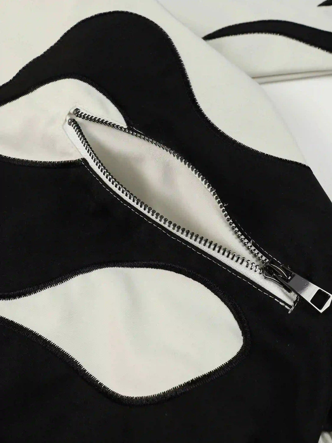 A detailed view of the black and white patchwork and zipper on a TALISHKO jacket, showcasing its unique style.