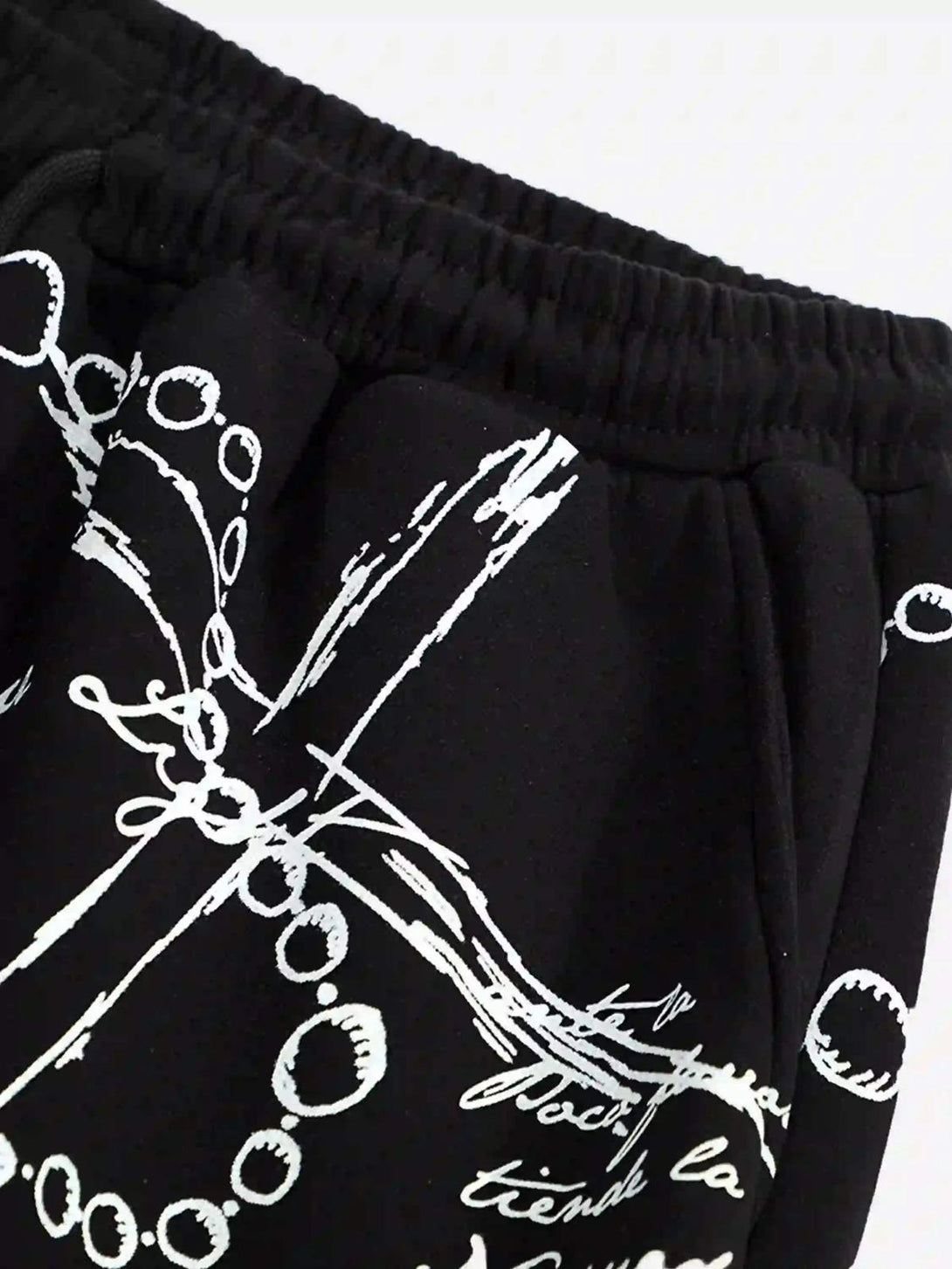 Close-up of TALISHKO hip-hop pants showcasing intricate white designs and elastic waistband.