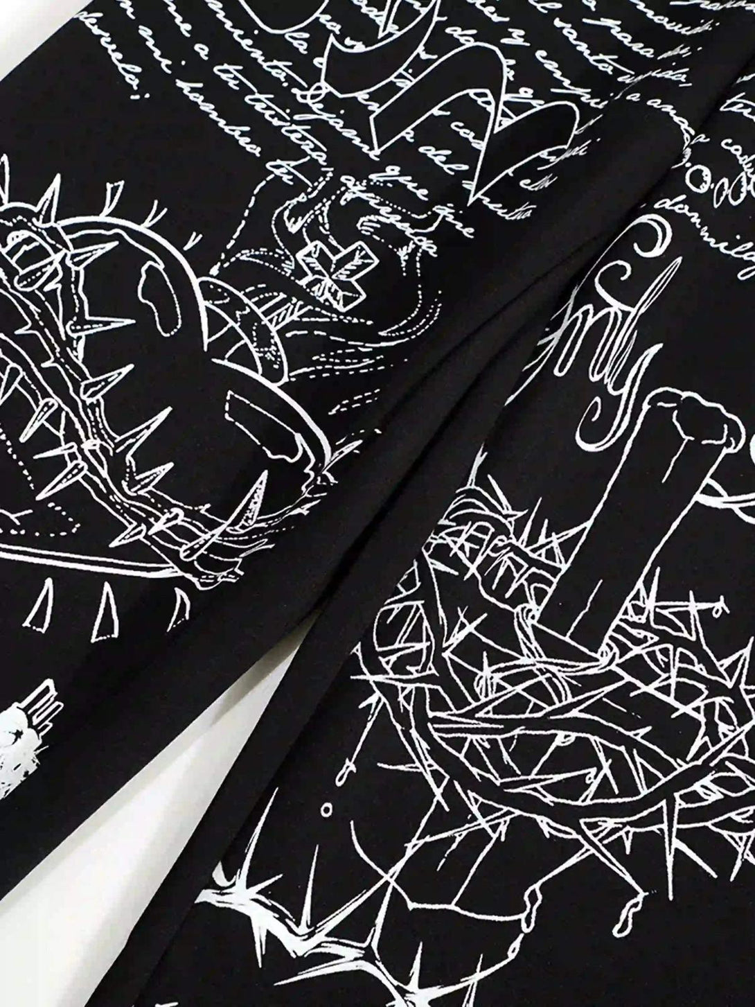 Intricate white designs and script on black hip-hop pants by TALISHKO, showcasing unique style.