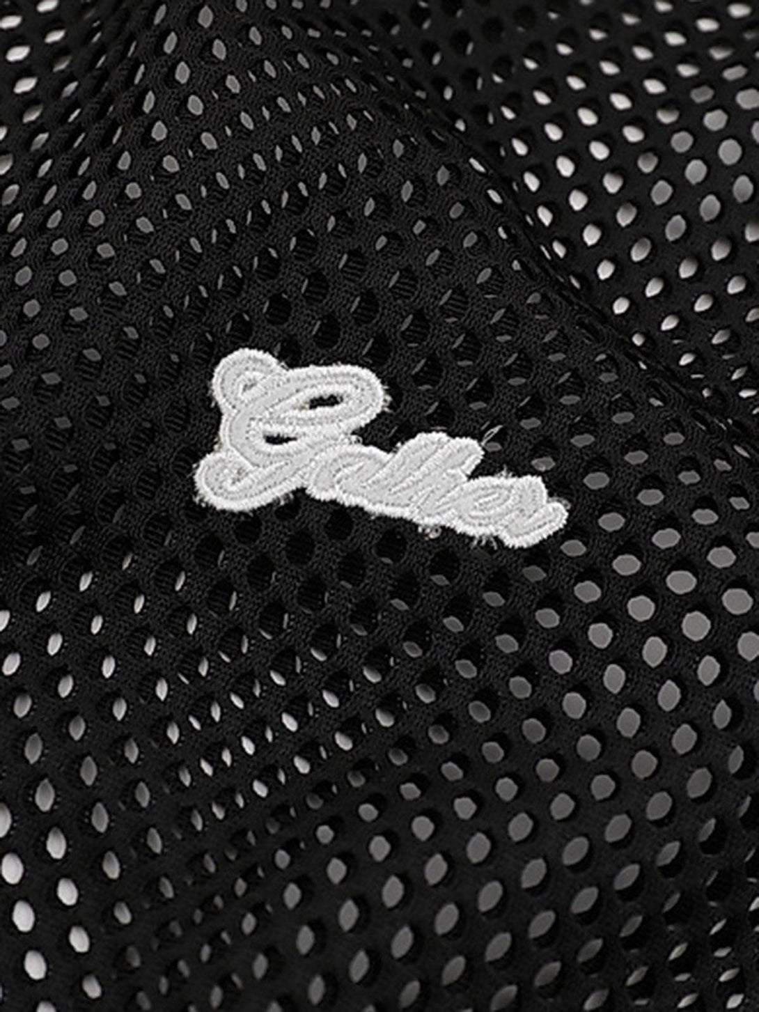 Mesh fabric detail with embroidered letters on a vest by TALISHKO, highlighting breathable design.
