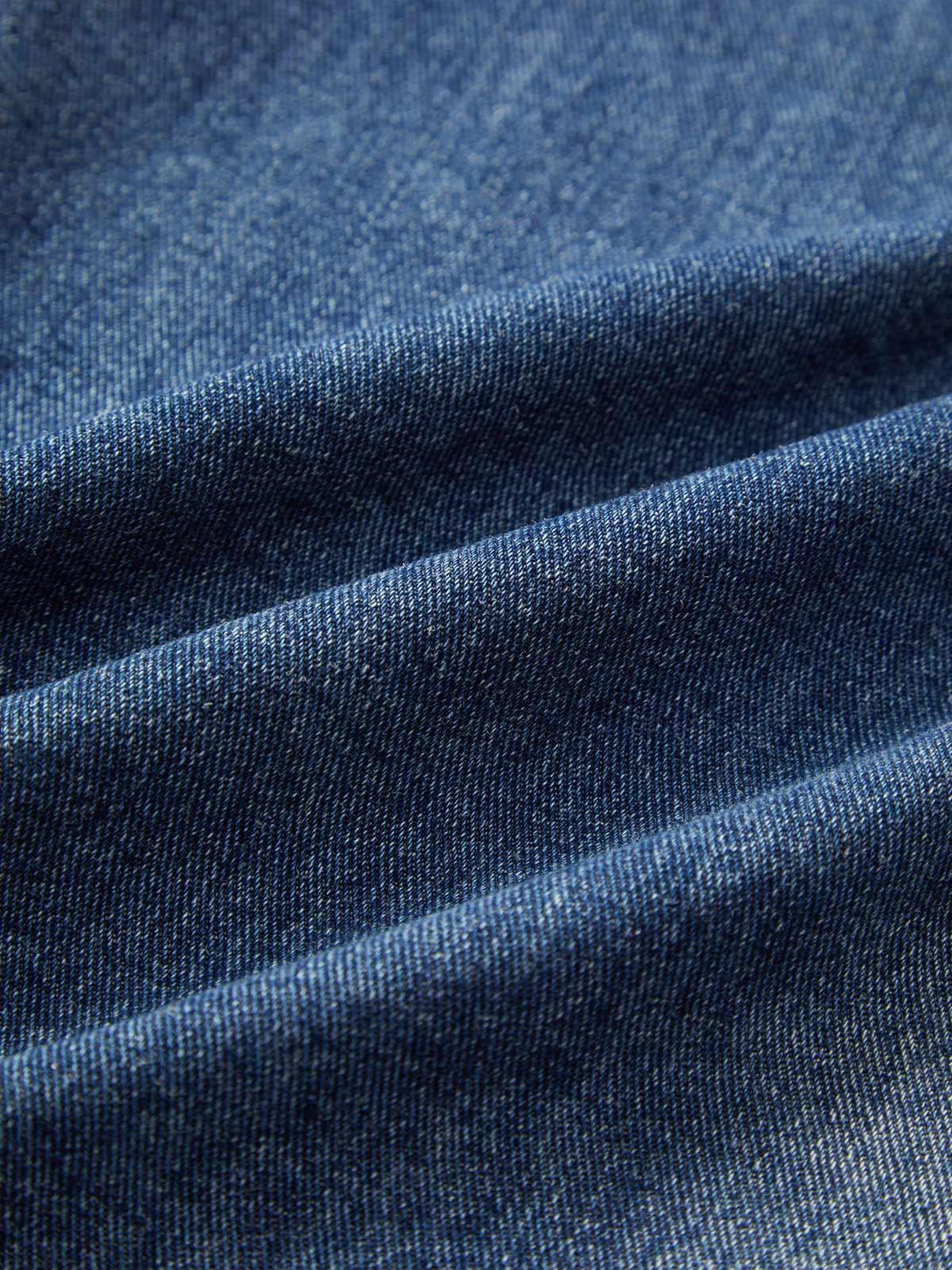 Zoomed-in texture of TALISHKO cargo jeans, highlighting the deep blue denim fabric.