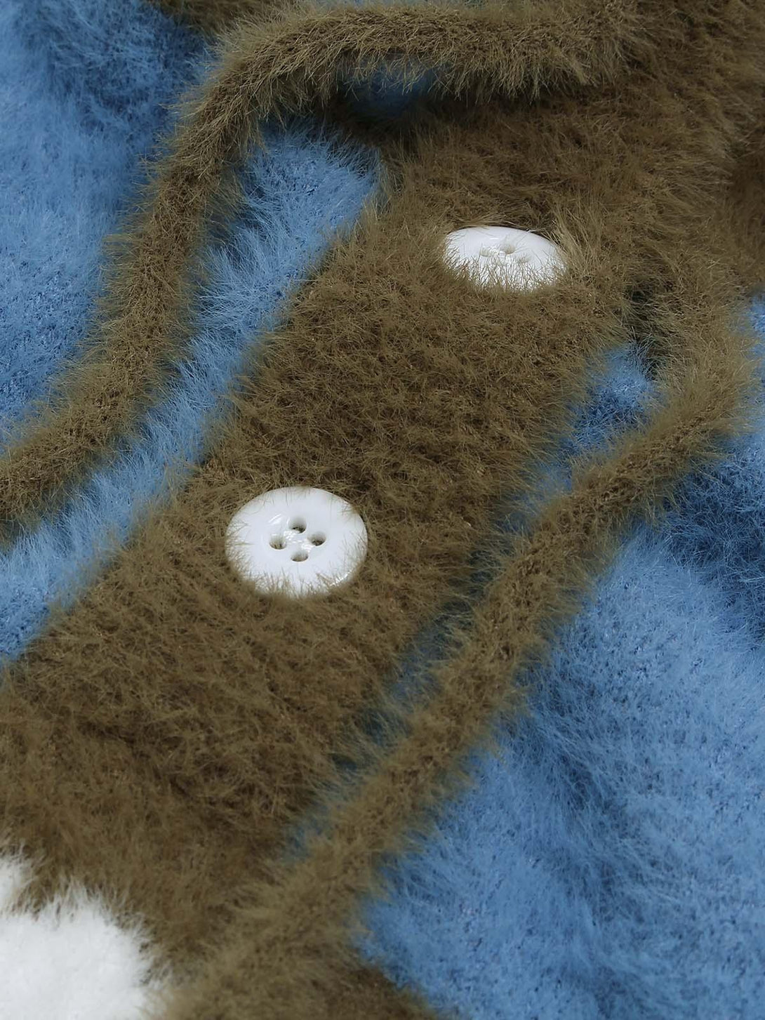Focusing on the plush texture of a blue and brown knit sweater, featuring buttons, by TALISHKO.