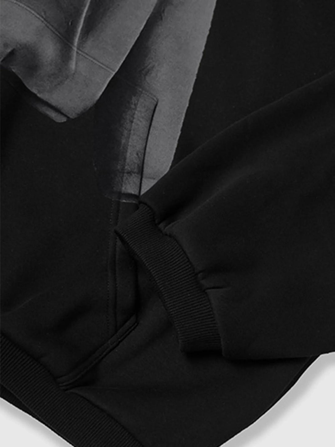 A detailed view of a black TALISHKO hoodie, highlighting its ribbed cuffs and pocket stitching.