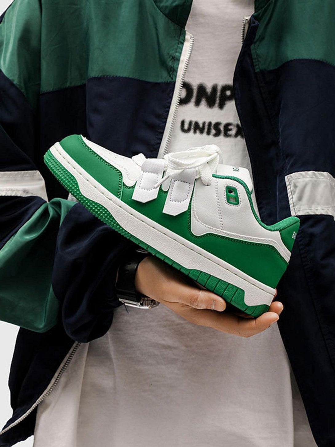 TALISHKO green and white casual sneakers held by a model, highlighting sporty streetwear flair.