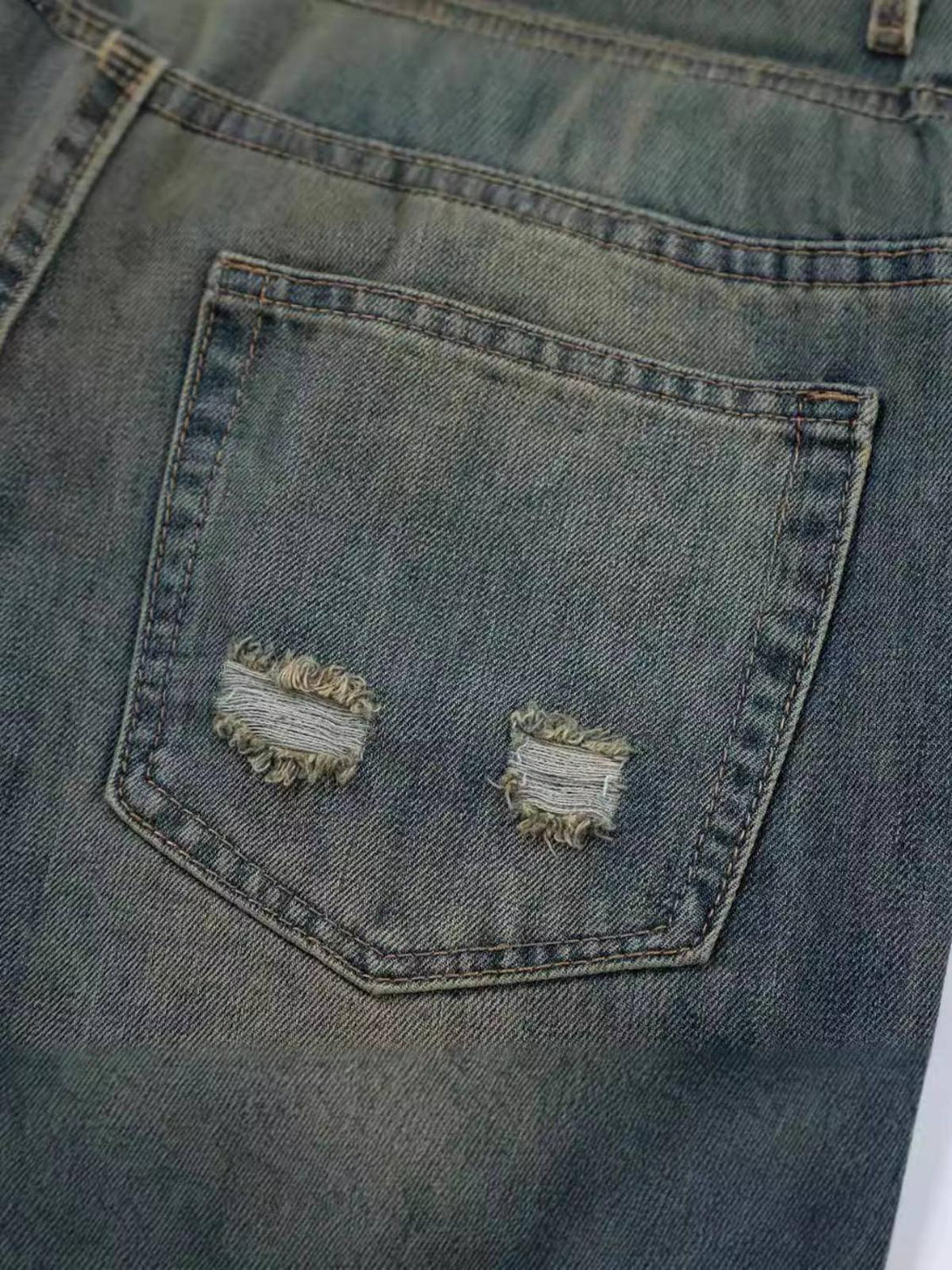 A detailed look at the back pocket of TALISHKO graffiti print jeans, highlighting distressed accents.