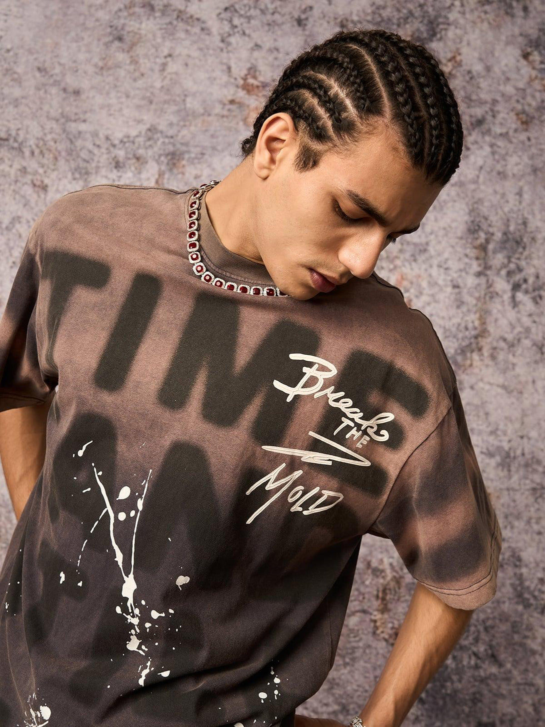 Model in TALISHKO ink splash letter print T-shirt, highlighting artistic design against a textured backdrop.