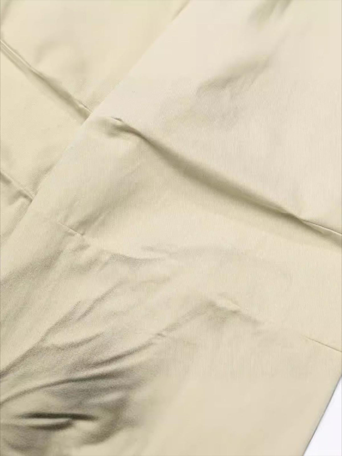 A detailed view of TALISHKO's inkjet pleated pants, highlighting the fabric's unique texture.