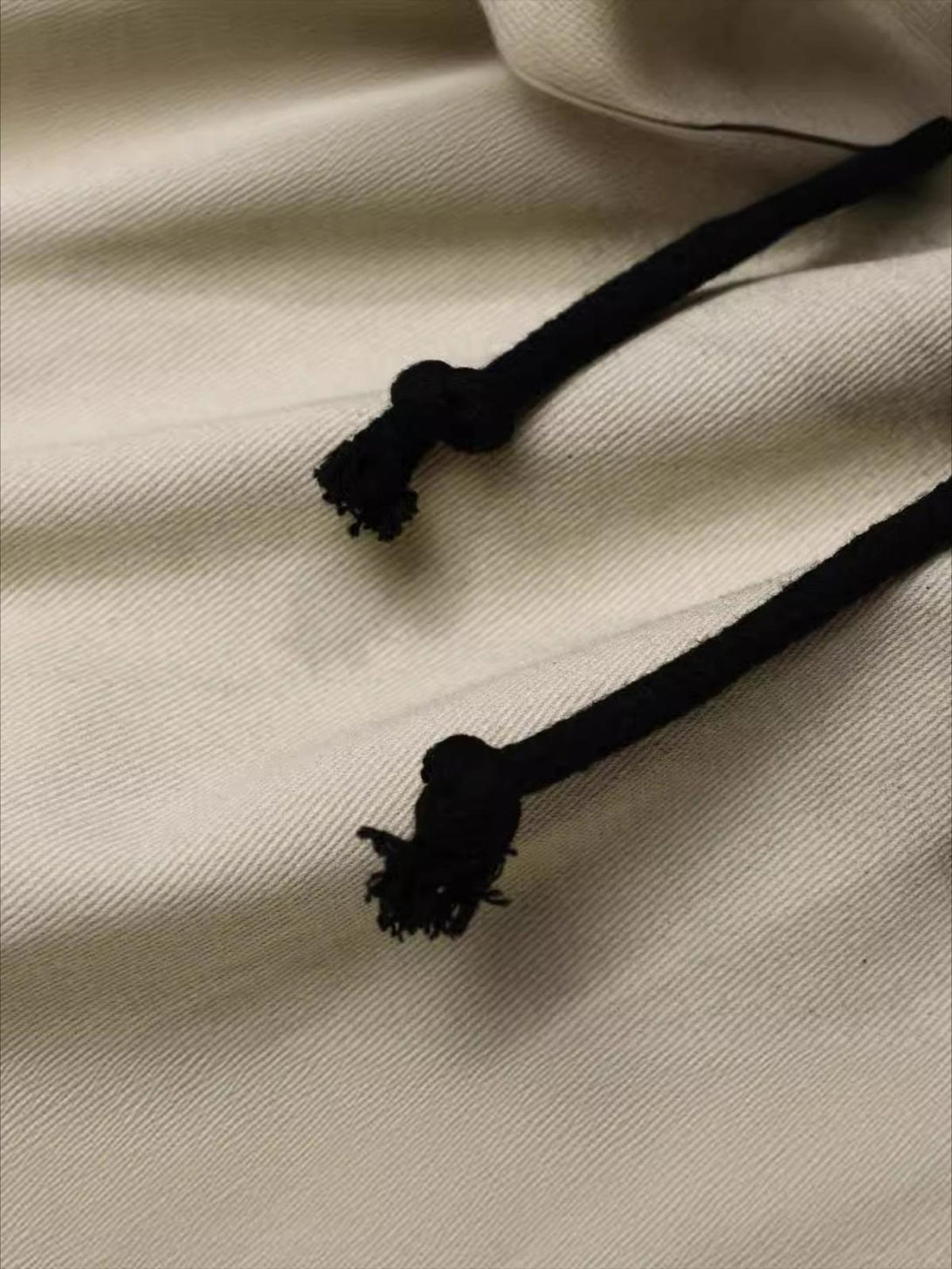 Zoomed-in view of TALISHKO's pleated pants, highlighting the intricate fabric texture and drawstring detail.